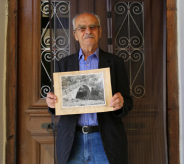 Ioannidis resident of Vovoussa village in Zagori showing an old photo of his villages stone bridge 360x320