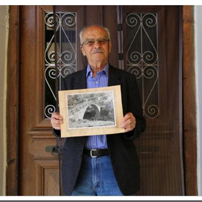Ioannidis resident of Vovoussa village in Zagori showing an old photo of his villages stone bridge
